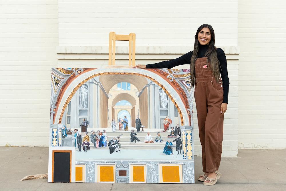 ASU grad Ariana Afshari poses next to her adaptation of "The School of Athens" by the Italian Renaissance artist Raphael.